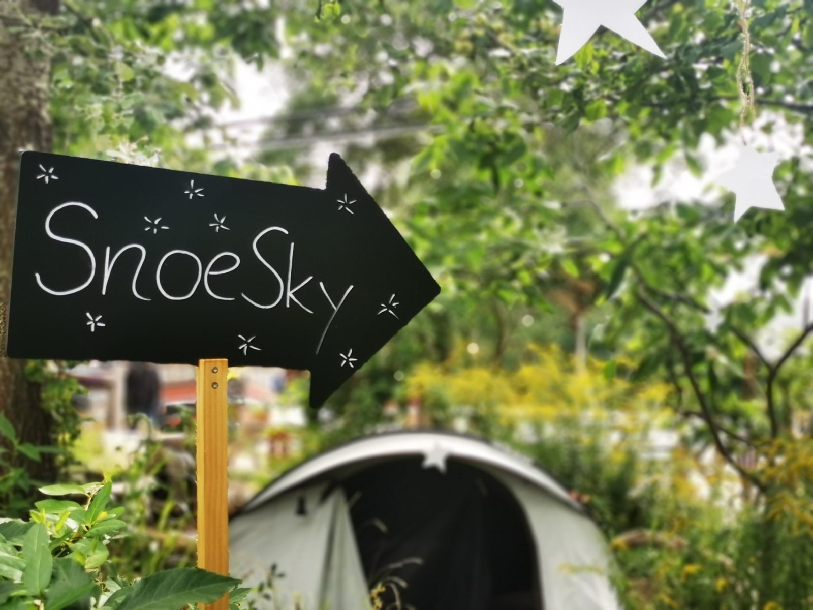  Ein Schild mit der Aufschrift SnoeSky zeigt auf ein Zelt im Hintergrund.